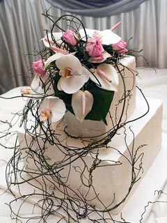 two tier small square wedding cake is covered with royal icing. Decorated with white Phalaenopsis Orchids