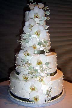 Round three tier wedding cake covered in royal icing and decorated with green Cymbidium Orchids